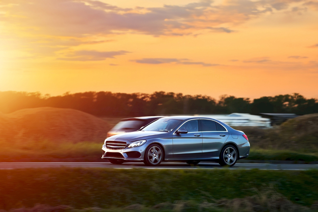 Ein Mercedes fährt in der Abendsonne über eine Straße. Mercedes gehört zu den sicheren Autos.